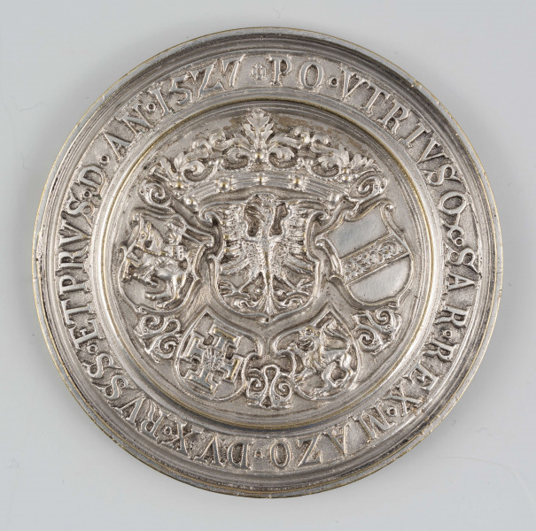 N/1489/ML - AV. W tondzie ujętym profilowanym otokiem popiersie króla w prawo w pątliku na głowie, w delii, z łańcuchem orderu Złotego Runa, ujęte wieńcem z liści akantu. W otoku napis rozdzielony na dole popiersiem władcy:
D . SIGIS . I . R . P . P . P . EF . AD . VIVAM . IMAGI . AETA . 60
W napisie w miejscu kropek znaki międzywyrazowe w postaci kółeczek.

RV. W tondzie ujętym profilowanym otokiem ukoronowana ozdobna tarcza z orłem polskim otoczona przez rozdzielone arabeską cztery mniejsze tarcze z herbami: Litwy, Prus, Rusi i Habsburgów. W otoku napis:
+ PO . VTRIVSQ . SAR . REX . MAZO . DVX . RVSS . ETPRVS . D . AN . 1527