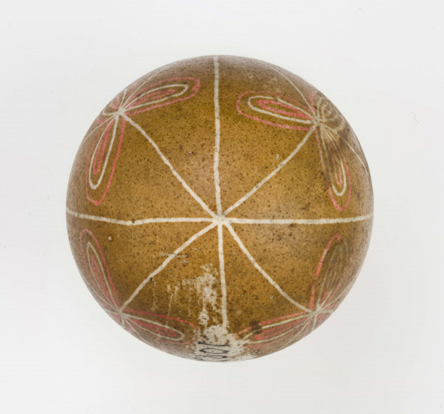 Technika batik. Podział podłużny na 4 części, podział poprzeczny na 2 części. Motyw trikwert. Barwa tła brązowa, barwa motywu biała i czerwona.