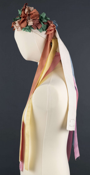 E/5038/ML - Strój głowy panny młodej wykonany jako rekonstrukcja. Wianek z papieru obszytego białym płótnem fabrycznym.  Z  wierzchu naszyte kolorowe wstążki poskładane i pozszywane na krzyż. W tyłu doszyte długie kolorowe wstążki, koloru: czerwonego, różowego, zielonego i niebieskiego.  