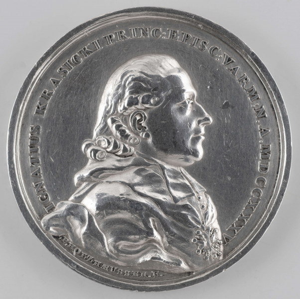 N/394/ML - AV. Popiersie biskupa w profilu w prawo, w sutannie, z orderem Orła Białego na piersiach. W otoku napis rozdzielony na dole przez wizerunek:
IGNATIUS KRASICKI PRINC : EPISC : VARM : N . A . MDCCXXXV
Sygnatura: .P. HOLZHAEUSSER.F.

RV. Czterowierszowy napis:
DIGNUM / LAUDE VIRUM / MUSA VETAT / MORI . 
Niżej pod poziomą kreską :
S.A.R. F.F. / A.MDCCLXXX
W otoku wieniec z gałązek laurowych, przewiązanych na dole wstążką.