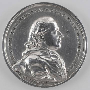 N/394/ML - AV. Popiersie biskupa w profilu w prawo, w sutannie, z orderem Orła Białego na piersiach. W otoku napis rozdzielony na dole przez wizerunek:
IGNATIUS KRASICKI PRINC : EPISC : VARM : N . A . MDCCXXXV
Sygnatura: .P. HOLZHAEUSSER.F.

RV. Czterowierszowy napis:
DIGNUM / LAUDE VIRUM / MUSA VETAT / MORI . 
Niżej pod poziomą kreską :
S.A.R. F.F. / A.MDCCLXXX
W otoku wieniec z gałązek laurowych, przewiązanych na dole wstążką.