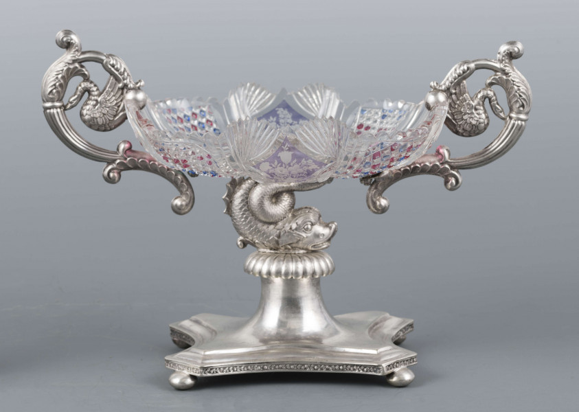 S/Mt/384/ML - Czara ze szkła bezbarwnego, miejscami barwionego powierzchniowo, płytka, owalna, profilowana, z dekoracją szlifowaną (wachlarzyki i szlif brylantowy) i trawioną (wzór kwiatowy) - utrzymana w stylu biedermeier. Umieszczona na figurce delfina z podstawą czworoboczną o wklęsłych bokach i ściętych narożach, z nóżkami w kształcie spłaszczonych kulek. Po bokach czary ucha w formie wolut z liśćmi akantu i motywem łabędzi. Brzeg podstawy obiega pas wici różanej.
Na brzegu podstawy sygnatura wklęsła kursywą: 
-  