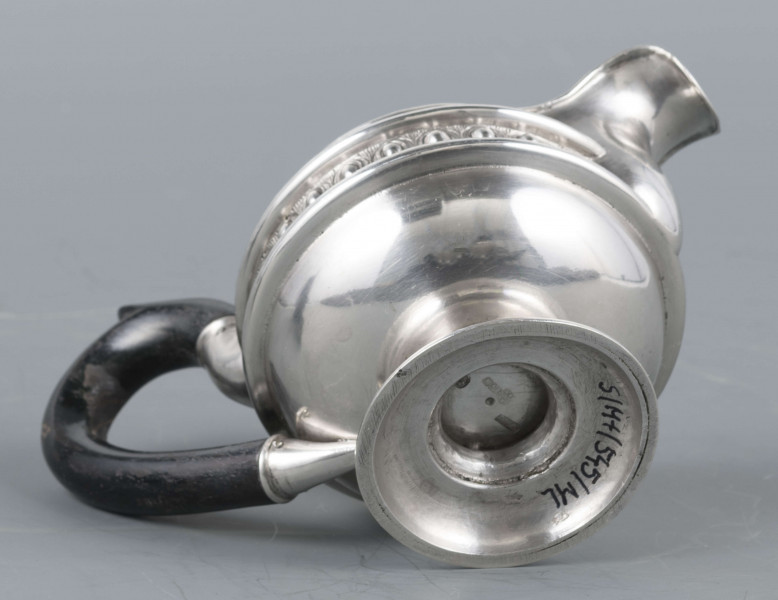 S/Mt/545/ML - Brzusiec w formie spłaszczonej kuli, pośrodku zdobiony repusowanym pasem kimationu obwiedzionego dwoma półwałkami, brzeg górny z okrągłym rantem, wylew wywinięty, zaokrąglony. Wnętrze złocone. Stopa okrągła profilowana, ucho drewniane malowane na czarno, osadzone w dwóch tulejkach . Na brzuscu pod górną krawędzią grawerowany ozdobny monogram 