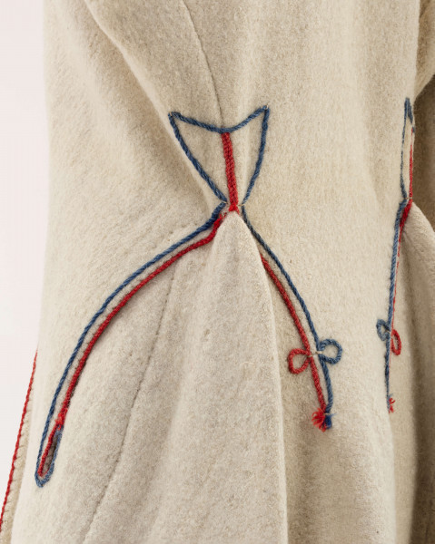 Sukmana kobieca, odświętna, szyta ręcznie z samodziałowego, folowanego sukna w kolorze białym. Nieodcinana w talii, przody bez zapięcia. Rękawy długie, lekko zwężone ku dołowi. Na bokach poniżej talii wstawione trójkątne kliny, które tworzą fałdy. W szwach łączących przody z klinami – tzw. ślepe kieszenie. Ozdobiona czerwonym i granatowym sznureczkiem wełnianym: na kołnierzyku, na przodzie,  dole rękawów oraz na bokach poniżej talii i przy kieszeniach. Często przepasywana była wełnianą krajką.