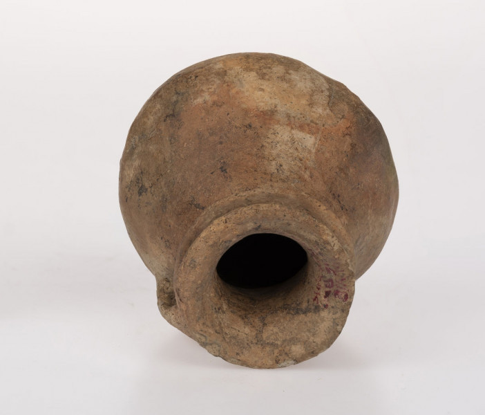 Flasza z kryzą. Szyjka lejkowato rozchylona o brzegu wywiniętym na zewnątrz i zaokrąglonej krawędzi wylewu, nieco powyżej nasady szyjki znajduje się kryza o zaokrąglonej krawędzi przechodząca w górny przyczep taśmowatego uszka; dolny przyczep ucha sięga połowy wysokości dwustozkowatego brzuśca, którego zaokrąglony załom przypada ok. 1/3 wys. naczynia (licząc od dna). Na obwodzie wklęsłego dna 5 niezbyt równomiernie rozmieszczonych guzków-nóżek. Surowiec-glina z drobnoziarnistym piaskiem. Barwa powierzchni zewnętrznej beżowo-ceglasta; wewnętrznej - beżowa. Przełom niewidoczny. Powierzchnia zewnetrzna gładzona, błyszcząca. Wypał dobry.