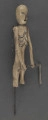 E/319/ML - Figurka z szopki, przedstawiająca śmierć, wykonana z drzewa, pomalowana białą farbą. Głowa o kształcie trójkątnym, wydłużonym. Oczy, nos i usta wydrążone i pomalowane srebrną farbą. Tułów krótki z zaznaczonymi plastycznie i zaznaczonymi srebrną i czarną farbą. Ręce ruchome w ramieniu, osadzone na drucie, w łokciu nieco zgięte z zaznaczonym plastycznie stawem łokciowym. Nogi proste, bez stóp, z silnie zgrubiałymi kolanami, z wyrzeźbionymi gwiazdkami pomalowanymi srebrną farbą. W rękach figurka trzyma kosę z drutu i cienkiej blaszki. Do ramienia przymocowany jest drut przechodzący z tyłu i założony za klamerkę wmontowaną w prawą nogę z tyłu. Drucik ten umożliwia poruszanie rękami figurki w czasie przedstawienia. W prawej nodze umocowany jest drut o haczykowatym zakończeniu.