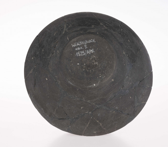 Naczynie wazowate - dwustożkowate; dno lekko wklęsłe z dołeczkiem w środku, wyraźnie wyodrębnione niewielką stopką; brzusiec dwustożkowaty, ostro profilowany; miejsce przejścia brzuśca w szyję zaznaczone wypukłą dookolna listwą; szyja niska, cylindryczna; wylew zaokrąglony, wywiniety na zewnatrz; górna część brzuśca zdobiona dookolnym rzędem narysowanych 