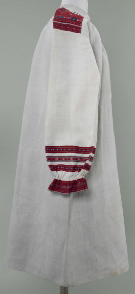 Koszula lniana o kroju przyramkowym, marszczonym. Ozdobiona na przyramkach i mankietach pereborami w kolorze czerwonym, granatowym i żółtym. Mankiety falbankami.