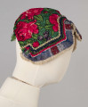 E/8141/ML - Czepek mężatki na płóciennej podszewce z zielonej cienkiej wełenki w amarantowe róże, fioletowe sasanki i jasnozielone listki. Marszczony na środku przodu i tyłu. Przód ozdobionymi kremowymi i granatowymi ząbkami, srebrną metaliczną wstążką oraz szeroką atłasową wstążką w kolorze granatowym w białe i czerwone kwiaty. Brzeg wykończony białą tiulową, drobno plisowaną kryzą. Przód wycięty w duży ząb w kształt płatka kwiatu.