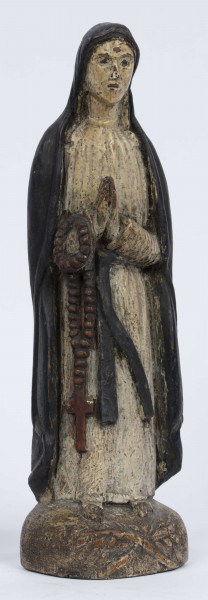 E/6363/ML - Rzeźba z drewna lipowego, polichromowana farbą olejną. Zakomponowana w jednym kawałku drewna na postumencie o formie owalnej z płaskorzeźbionym motywem dwóch skrzyżowanych gałęzi. Postać stojąca przedstawia Matkę Boską Różańcową. Twarz owalna, głęboko osadzone oczy, prosty i szeroki nos, małe pełne usta. Ręce zgięte w łokciach: duże dłonie złożone do modlitwy. Na przedramieniu prawej ręki brązowy różaniec o płaskich paciorkach, zakończony dużym krzyżem. Postać odziana w białą prostą suknię, gładko wykończoną pod szyją i przewiązaną granatową szarfą. Na głowie granatowa szata spełniająca jednocześnie rolę peleryny spływającej z ramion ku dołowi i spowijającej całą postać.