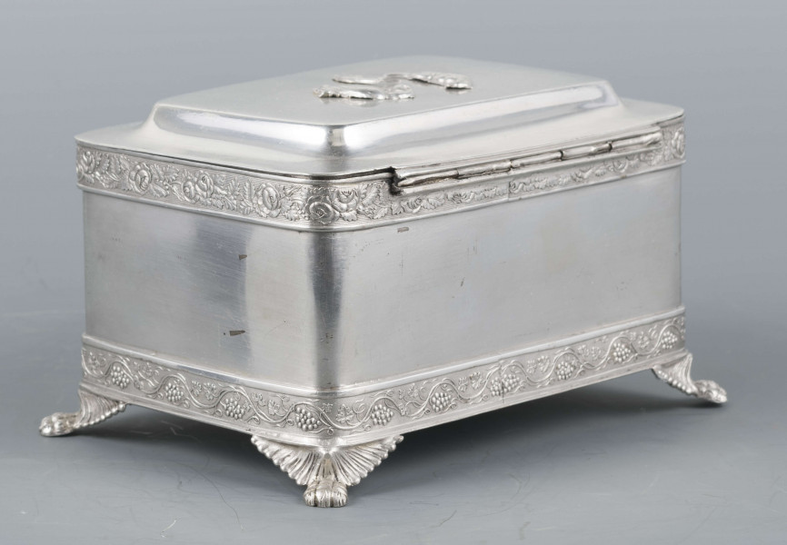 S/Mt/354/ML - Cukiernica prostokątna o lekko zaokrąglonych narożach, na czterech nóżkach w formie uskrzydlonych lwich łap, z profilowanym wieczkiem. Brzegi obwiedzione moletowaną taśmą: u dołu z motywem winnej łozy, u góry - wici różanej.Szyld zamka zdobi plakieta z girandą róż, druga - na wieczku - jest uszkodzona a przez to nieczytelna.
Na dnie sygnatury kursywa we wklesłych owalnych ramkach:
- K.Rotkiel
- w lublinie
Przedzielone okrągłą puncą z próbą 