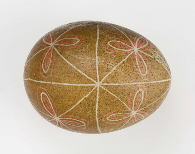 Technika batik. Podział podłużny na 4 części, podział poprzeczny na 2 części. Motyw trikwert. Barwa tła brązowa, barwa motywu biała i czerwona.