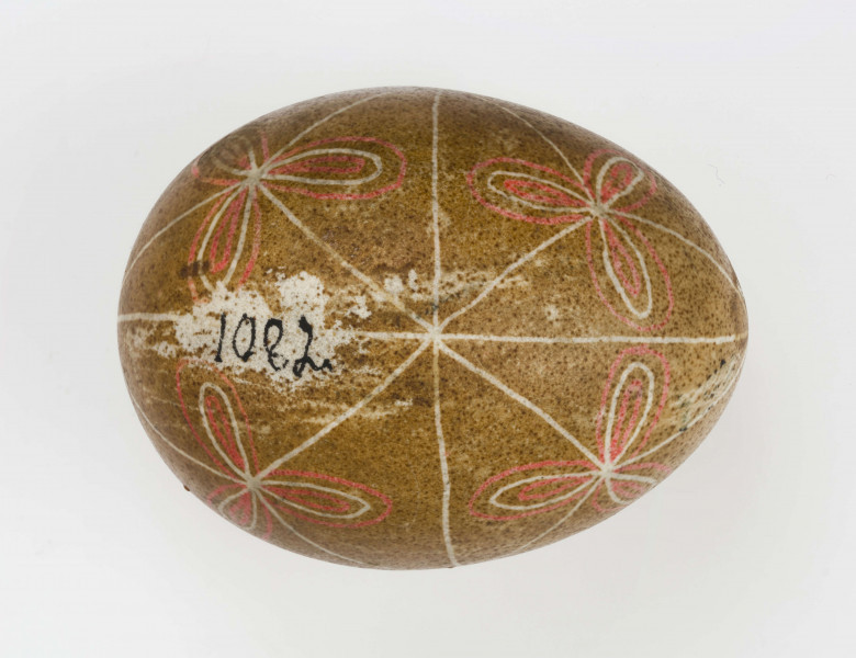 Technika batik. Podział podłużny na 4 części, podział poprzeczny na 2 części. Motyw trikwert. Barwa tła brązowa, barwa motywu biała i czerwona.