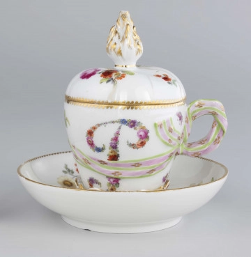 S/CS/1240/1-2/ML Biała porcelana z ornamentami kwiatowymi; na filiżance stylizowana litera P . Filiżankę zdobi motyw barwnej wstążeczki , ktorej wiązanie w kokardkę stanowi element uszka.