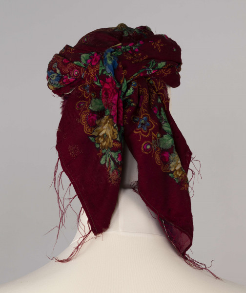 E/516/ML - Czepek mężatki. Denko wewnętrzne wykonane z plecionej siatki zielonej. Z wierzchu chustka fabryczna koloru ciemnoczerwonego w kwiaty wiązana na tekturowej obręczy. Końce chustki zwisają do tyłu.