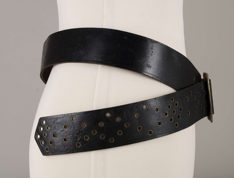 E/706/ML - Pas męski wykonany ze skóry koloru czarnego, z mosiężną klamrą. Ozdobiony ornamentem w postaci punktów wytłaczanych stemplem. Dziurki obłożone mosiężnymi kółeczkami.