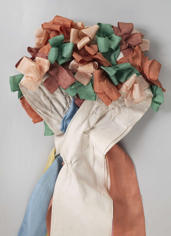 E/5038/ML - Strój głowy panny młodej wykonany jako rekonstrukcja. Wianek z papieru obszytego białym płótnem fabrycznym.  Z  wierzchu naszyte kolorowe wstążki poskładane i pozszywane na krzyż. W tyłu doszyte długie kolorowe wstążki, koloru: czerwonego, różowego, zielonego i niebieskiego.  