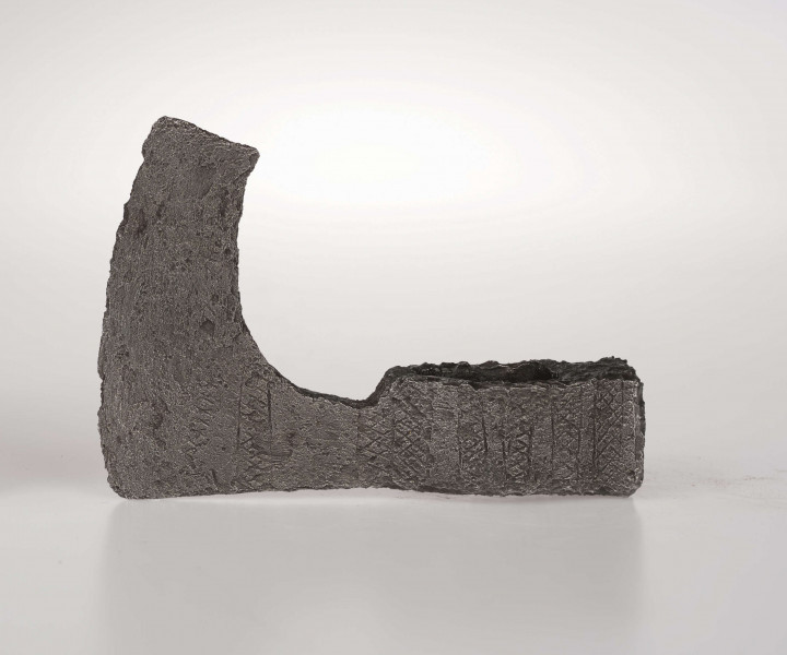 Czekan żelazny z guzowatym obuchem. Ostrze łukowato wygięte zakończone ukośnie ściętą brodą. Osada, szyjka i żeleźce zdobione obustronie pionowymi nacięciami wypełnionymi kratką z ukośnych nacięć Ornament na obu stronach różni sie nieco układem Na żeleźcu z jednej strony są umieszczone 5 nacieć w kształcie X