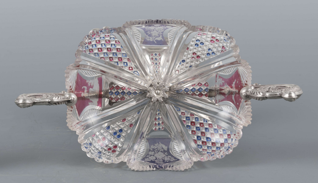 S/Mt/384/ML - Czara ze szkła bezbarwnego, miejscami barwionego powierzchniowo, płytka, owalna, profilowana, z dekoracją szlifowaną (wachlarzyki i szlif brylantowy) i trawioną (wzór kwiatowy) - utrzymana w stylu biedermeier. Umieszczona na figurce delfina z podstawą czworoboczną o wklęsłych bokach i ściętych narożach, z nóżkami w kształcie spłaszczonych kulek. Po bokach czary ucha w formie wolut z liśćmi akantu i motywem łabędzi. Brzeg podstawy obiega pas wici różanej.
Na brzegu podstawy sygnatura wklęsła kursywą: 
-  