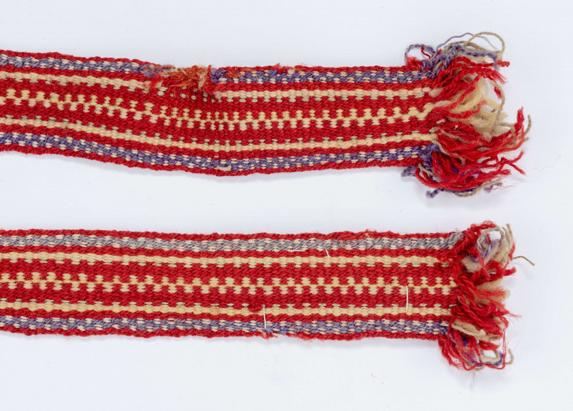 Krajka wełniana. Tło czerwone. Pasy fioletowo-kremowe, seledynowe, zielono-czerwone i kremowo-czerwone