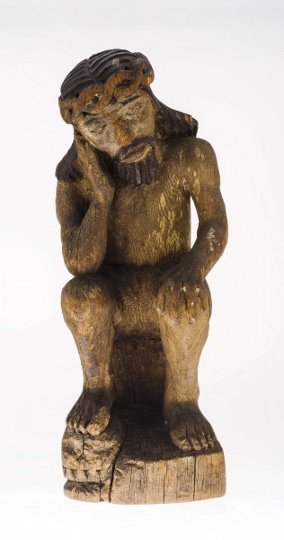 Figura Chrystusa Frasobliwego, pochylona w prawo głowa, wykonana w drewnie lipowym, polichromowana. Twarz potraktowana realistycznie. Korona cierniowa z przeplatanego wałka (kształt ósemki). Ślady cierni. Włosy opadające na ramiona modelowane dość szerokimi podłużnymi żłobieniami. Na włosach ślady polichromii koloru czarnego. Broda koloru brązowego, zaznaczona mocnymi żłobieniami. Prawa dłoń przy policzku. Faktura ciała modelowana gładko. Perizonium krótkie, lekko fałdowane. Prawa stopa na czaszce.