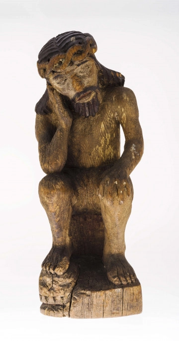 Figura Chrystusa Frasobliwego, pochylona w prawo głowa, wykonana w drewnie lipowym, polichromowana. Twarz potraktowana realistycznie. Korona cierniowa z przeplatanego wałka (kształt ósemki). Ślady cierni. Włosy opadające na ramiona modelowane dość szerokimi podłużnymi żłobieniami. Na włosach ślady polichromii koloru czarnego. Broda koloru brązowego, zaznaczona mocnymi żłobieniami. Prawa dłoń przy policzku. Faktura ciała modelowana gładko. Perizonium krótkie, lekko fałdowane. Prawa stopa na czaszce.