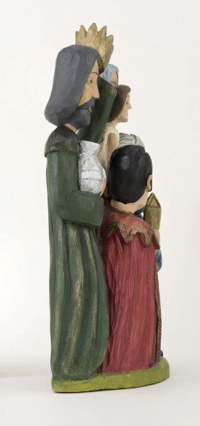 Rzeźba z drewna lipowego, technika strugania, polichromowana farbami plakatowymi. Na postumencie w kształcie nieregularnego owalu o wym. 23 x 13 x 1,5 cm, w kolorze seledynowym, zakomponowane zostały cztery postacie. W głębi z lewej strony postać króla (wys. 38 cm) w granatowej długiej szacie i zielonym płaszczu, z okrągłym kołnierzem. Król w lewej podniesionej ręce trzyma złotą koroną, w prawej – srebrny dzbanek. Z prawej strony postać Matki Boskiej (wys. 38,5 cm) z Dzieciątkiem (wys. 17 cm) w kremowej sukience, na prawym ręku. MB w czerwonej długiej sukni, zielonym płaszczu i niebieskiej chustce na głowie. Przed MB z lewej strony klęczy król (wys. 24,5 cm) w czerwonym płaszczu i czarnej sukni, który w rękach trzyma złotą szkatułkę. Z prawej strony klęczy król (wys. 28,5 cm) w granatowym płaszczu o niebieskim podbiciu i mankietach, brązowych spodniach, granatowych butach sięgających do połowy łydki. Na głowie ma złotą koronę na czerwonej czapce, otoczonej białym zawojem. W lewej ręce trzyma złotu kielich. 
