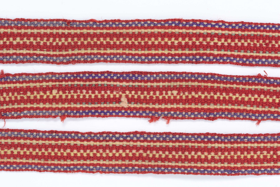 Krajka wełniana. Tło czerwone. Pasy fioletowo-kremowe, seledynowe, zielono-czerwone i kremowo-czerwone