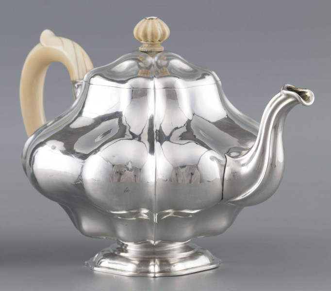 S/Mt/500/ML - Korpus silnie wybrzuszony w części środkowej, puklowany pionowo, profile przechodzą na pokrywke w formie wieczka na zawiasie. Stopa kwadratowa wielolistna, wylew w formie dzióbka, ucho kościane osadzone w dwóch tulejkach,
uchwyt na pokrywce kościany, profilowany. Wnetrze złocone.
Na spodzie stopy sygnatura:
- 