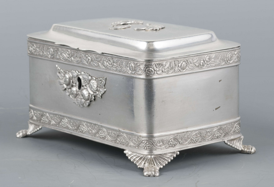 S/Mt/354/ML - Cukiernica prostokątna o lekko zaokrąglonych narożach, na czterech nóżkach w formie uskrzydlonych lwich łap, z profilowanym wieczkiem. Brzegi obwiedzione moletowaną taśmą: u dołu z motywem winnej łozy, u góry - wici różanej.Szyld zamka zdobi plakieta z girandą róż, druga - na wieczku - jest uszkodzona a przez to nieczytelna.
Na dnie sygnatury kursywa we wklesłych owalnych ramkach:
- K.Rotkiel
- w lublinie
Przedzielone okrągłą puncą z próbą 