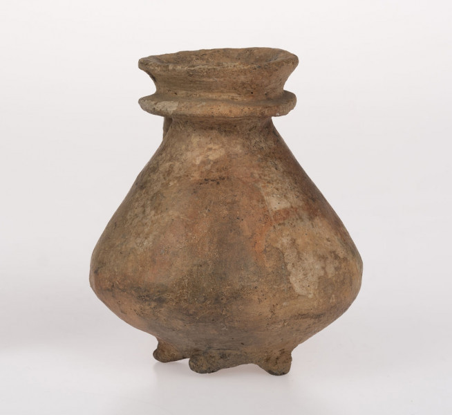 Flasza z kryzą. Szyjka lejkowato rozchylona o brzegu wywiniętym na zewnątrz i zaokrąglonej krawędzi wylewu, nieco powyżej nasady szyjki znajduje się kryza o zaokrąglonej krawędzi przechodząca w górny przyczep taśmowatego uszka; dolny przyczep ucha sięga połowy wysokości dwustozkowatego brzuśca, którego zaokrąglony załom przypada ok. 1/3 wys. naczynia (licząc od dna). Na obwodzie wklęsłego dna 5 niezbyt równomiernie rozmieszczonych guzków-nóżek. Surowiec-glina z drobnoziarnistym piaskiem. Barwa powierzchni zewnętrznej beżowo-ceglasta; wewnętrznej - beżowa. Przełom niewidoczny. Powierzchnia zewnetrzna gładzona, błyszcząca. Wypał dobry.