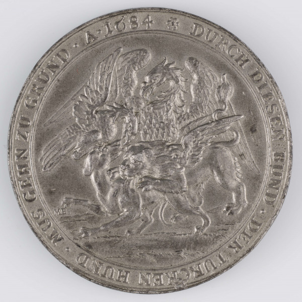 N/1533/ML - AV. Trzy postacie męskie trzymające łańcuch, stojące na liściach koniczyny. Wokół głów napisy objaśniające, od lewej:
1) IOH . III . REX . POLONIA . 
2) LEOPOLDVS I . ROM : I :
3) M : A : I : DVX VENETIA
W otoku napis rozdzielony przez kompozycję:
DIE EINTRACHTS TREV .  -  DIS HEL - DEN DREY . - MIT SIG
EREREV . 
Na dole w poziomie:
CONFOEDERATIO / ET / CONCORDIA . 
Monogram: MB .

RV.  Kompozycja symboliczna: dwa orły i skrzydlaty lew szarpiące psa. W otoku napis poprzedzony rozetką:
DURCH DIESEN BUND . DER TURCKEN HUND . MUS GEHEN ZU GRUND . A . 1684
Po lewej monogram: MB .
