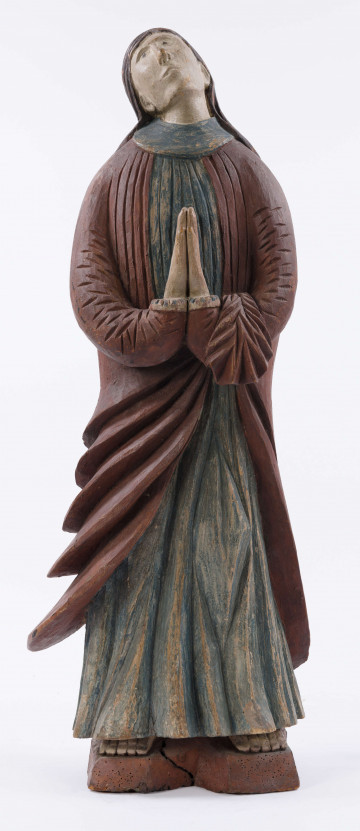 E/16137/ML - Rzeźba drewniana, pełna, polichromowana, przedstawiająca św. Anny. Na postumencie w kształcie nieregularnego prostokąta, zakomponowana postać świętej, w długiej sukni, układanej w pionowe fałdy. U góry fałdy są drobniejsze, u dołu fałdy grubsze, pod szyją kołnierzyk w kształcie półokrągłej plisy. Na sukni kubraczek w kolorze brązowym, sięgający do połowy łydki, o połach zaokrąglonych u dołu. Kubrak z długimi rękawami jest dopasowany w czasie. Z przodu do pasa podkreślony jest dość wąskimi pionowymi żłobieniami, od pasa szerszymi biegnącymi ukośnie fałdami, zaś na rękawach ukośnymi nieregularnymi żłobieniami. Ręce złożone na piersiach do modlitwy. Głowa wzniesiona lekko do góry i lekko przechylona w prawo. Włosy brązowe, zaznaczone z przedziałkiem pośrodku, opadające na plecy, podkreślone żłobieniami. Nos prosty wydatny, usta wąskie, oczy owalne czarne, brwi cienkie łukowate czarne. Twarz i ręce pokryte cielistą farbą. Widoczne uszy. Spod sukni widoczne bose stopy.

Konserwacja: 1988 r.