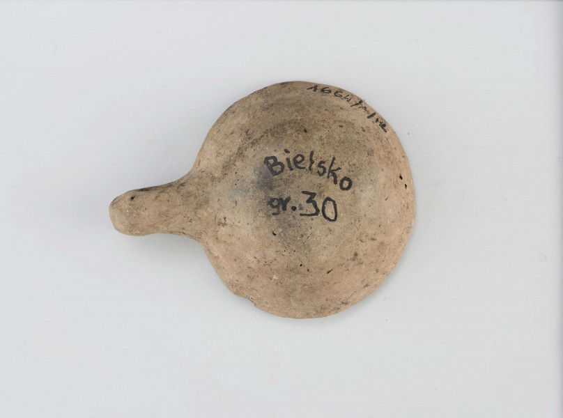 czerpak; dno spłaszczone, niewyodrębnione, ścianki rozchylone na zewnątrz, krawędź ścięta płasko; ucho wałkowate, duże, grube wystające ponad krawędź