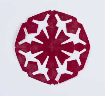 Wycinanka czerwona w formie ośmioboku, w centrum kwiat o trapezowatych płatkach, przedłużenie, których stanowią romby, otok z rombów i ściętych stożków.