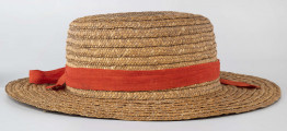 Kapelusz ze słomy owsianej o prostym denku i rondzie płaskim. Upleciony techniką warkoczową. Warkocze bez ząbków, zszyte cienkimi szarymi nićmi. Denko otoczone czerwoną wąską wstążką, zakończone kokardą. 