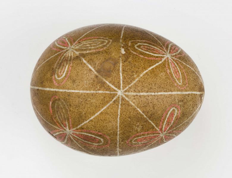 Technika batik. Podział podłużny na 4 części, podział poprzeczny na 2 części. Motyw trikwert. Barwa tła brązowa, barwa motywu biała i czerwona.