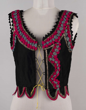 E/5504/ML - Gorset z czarnego aksamitu, podszyty szarą lnianą podszewką. Ozdobiony tasiemką w kolorze amarantowym, niebieskim i srebrnym – na taszkach oraz wzdłuż wycięć pach i dekoltu. Obszyte dziurki jako otwory do przeciągnięcia wiązania.