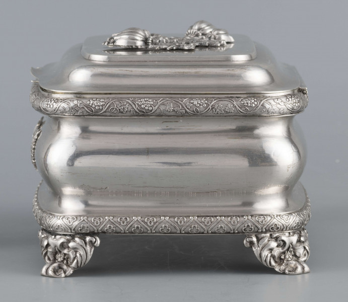 S/Mt/469/ML - Cukiernica prostokątna o zaokrągłonych narożach, profilowana, na czterech akantowych nóżkach. Brzeg dolny i górny obwiedzione półwałkiem zmoletowanej taśmy: u góry z wzorem winorośli, na dole - trójliścia.Brzeg wieczka fasetowany, z przodu lekko wywinięty tworzy uchwyt. Na wieczku nałożona półplastyczna plakieta w postaci  asymetrycznej gałązki kwiatowej. Szyld zamka stanowi sztancowana plakieta z motywem winorośli. Wnętrze złocone.
Na dnie sygnatura wypukła we wklęsłych ramkach:
- J.Suchocki
- w Lublinie
i punca z oznaczeniem próby 