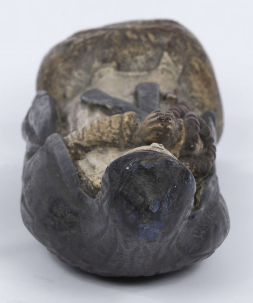 E/6363/ML - Rzeźba z drewna lipowego, polichromowana farbą olejną. Zakomponowana w jednym kawałku drewna na postumencie o formie owalnej z płaskorzeźbionym motywem dwóch skrzyżowanych gałęzi. Postać stojąca przedstawia Matkę Boską Różańcową. Twarz owalna, głęboko osadzone oczy, prosty i szeroki nos, małe pełne usta. Ręce zgięte w łokciach: duże dłonie złożone do modlitwy. Na przedramieniu prawej ręki brązowy różaniec o płaskich paciorkach, zakończony dużym krzyżem. Postać odziana w białą prostą suknię, gładko wykończoną pod szyją i przewiązaną granatową szarfą. Na głowie granatowa szata spełniająca jednocześnie rolę peleryny spływającej z ramion ku dołowi i spowijającej całą postać.