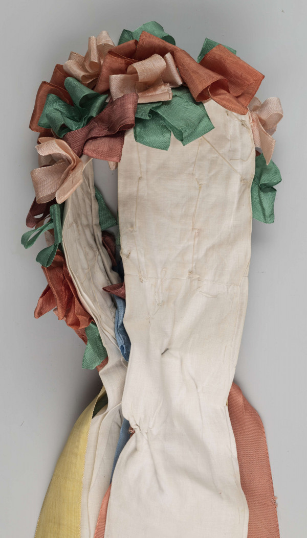 E/5038/ML - Strój głowy panny młodej wykonany jako rekonstrukcja. Wianek z papieru obszytego białym płótnem fabrycznym.  Z  wierzchu naszyte kolorowe wstążki poskładane i pozszywane na krzyż. W tyłu doszyte długie kolorowe wstążki, koloru: czerwonego, różowego, zielonego i niebieskiego.  