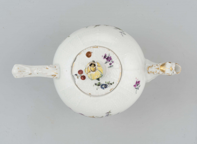 Imbryk kulisty lekko zwężony ku dołowi, wokół wylewu zdobiony plastyczną plecionka w typie Alt-Ozier. Dziobek rurkowy zakończony rozwartym smoczym pyskiem podkreślonym plastycznym liściem akantu. Ucho rokokowe w kształcie litery 