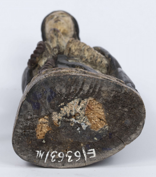 E/6363/ML - Rzeźba z drewna lipowego, polichromowana farbą olejną. Zakomponowana w jednym kawałku drewna na postumencie o formie owalnej z płaskorzeźbionym motywem dwóch skrzyżowanych gałęzi. Postać stojąca przedstawia Matkę Boską Różańcową. Twarz owalna, głęboko osadzone oczy, prosty i szeroki nos, małe pełne usta. Ręce zgięte w łokciach: duże dłonie złożone do modlitwy. Na przedramieniu prawej ręki brązowy różaniec o płaskich paciorkach, zakończony dużym krzyżem. Postać odziana w białą prostą suknię, gładko wykończoną pod szyją i przewiązaną granatową szarfą. Na głowie granatowa szata spełniająca jednocześnie rolę peleryny spływającej z ramion ku dołowi i spowijającej całą postać.