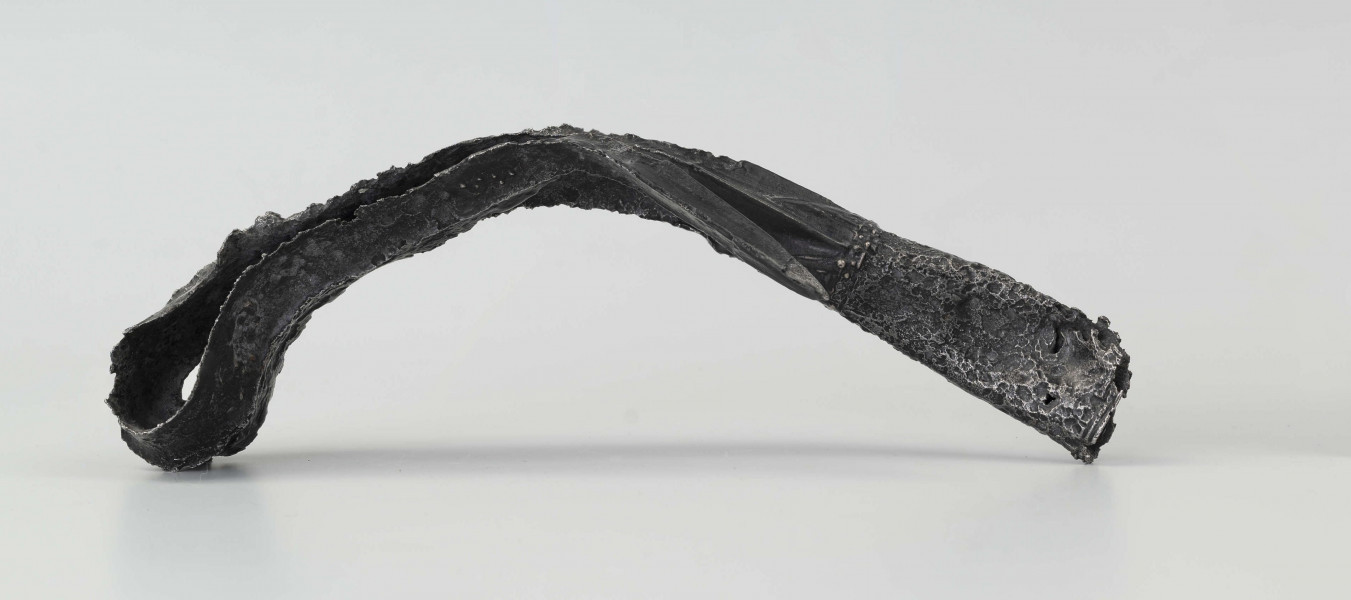 Żelazny grot broni drzewcowej zdobiony wyjątkową, srebrną inkrustacją jest częścią uzbrojenia włożonego do grobu ciałopalnego wojownika z początku III w. n.e. 
Grób przedstawiciela ludności kultury przeworskiej został odkryty przypadkowo w 1959 roku. 
Oprócz trzech grotów, pochówkowi wojownika towarzyszyły: żelazne umbo, dwie ostrogi, tok brązowy (prawdopodobnie okucie drzewca oszczepu) a także żelazny miecz z miedziana inkrustacją wyobrażającą rzymskich bogów. Pochowany na terenie obecnej wsi Podlodów wojownik należał do elity wojskowej przedstawicieli kultury przeworskiej. Liść grotu jest smukły i długi, a u podstawy cylindrycznej i krótkiej tulejki znajduje się żeberko. Na obydwu częściach grotu znajdują się zdobienia inkrustowane srebrem - znaki o znaczeniu symbolicznym: trójkąty sferyczne, punkty, podwójne widełki. Przypominają one symbole religijne (ewentualnie znaki magiczne lub własnościowe) - tamgi. Niektórzy badacze zakładają, że mogły one zostać przejęte przez Sarmatów. 
Wymiary dodatkowe: szer. 4,0 cm 