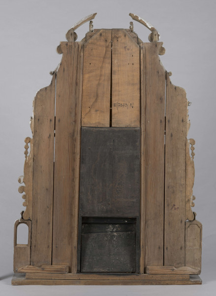 E/7373/ML - Ołtarzyk składa się z 3 części: podstawy i 2 pięter. Oba piętra podzielone na 3 pola (środkowe 24 cm, boczne 13,5 cm) przez kolumny. Podstawa posiadająca wysuniętą część środkową, ozdobiona jest 4 krzyżami greckimi wpisanymi w gwiazdę złot. Podstawę flankują 2 małe ołtarzyki: prawe brak przedstawienia, po lewej Madonna – złota postać na owalnym srebrnym polu, z granatową aureolą, nad nią na granatowym tle – 4 złote gwiazdki. Prawy ołtarzyk nad brakującym przedstawieniem ma złotą gwiazdkę. Lewemu jej brak. Górne pole podstawy zdobią 2 kolumienki oraz złote guzy pomiędzy. 
I piętro w części środkowej, pomiędzy kolumnami z tympanonem z głową aniołka i klęczącymi aniołami na daszku, postać Chrystusa Ukrzyżowanego w kolorze srebrnym, wraz ze złotymi  inskrypcją i pionowymi ząbkami. Po bokach, symetrycznie, przedstawienia  św. Mikołaja w złotej czapce biskupiej, na owalnej podstawie, z jedną ręką uniesioną , a druga opuszczoną trzymającą rękojeść. Ponad stylizowany złoty ornament roślinny. Całość piętra flankowana ornamentem przypominającym liście akantu i ślimacznice. 
II piętro w częściach bocznych zamknięte jest spływami wolutowymi , na polach po złotej kolumience/sterczynie i gwieździe. W części środkowej oleodruk ze św. Józefem z Dzieciątkiem, w złotej ramce. Całość wieńczą postaci ornatów w kolorze srebrnym i złote niepełne spływy wolutowe ze ślimacznicą. 
Brak wielu elementów. Plecy ołtarzyka stanowi 6 deseczek o szer. 10,5 cm i grubości 1,2 cm.