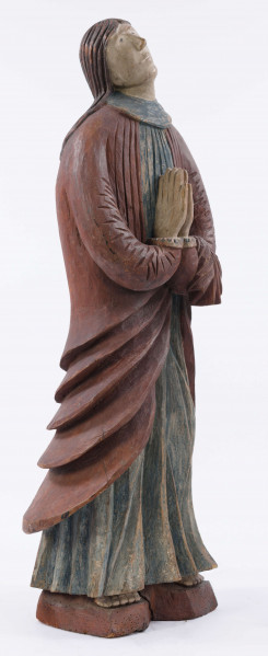 E/16137/ML - Rzeźba drewniana, pełna, polichromowana, przedstawiająca św. Anny. Na postumencie w kształcie nieregularnego prostokąta, zakomponowana postać świętej, w długiej sukni, układanej w pionowe fałdy. U góry fałdy są drobniejsze, u dołu fałdy grubsze, pod szyją kołnierzyk w kształcie półokrągłej plisy. Na sukni kubraczek w kolorze brązowym, sięgający do połowy łydki, o połach zaokrąglonych u dołu. Kubrak z długimi rękawami jest dopasowany w czasie. Z przodu do pasa podkreślony jest dość wąskimi pionowymi żłobieniami, od pasa szerszymi biegnącymi ukośnie fałdami, zaś na rękawach ukośnymi nieregularnymi żłobieniami. Ręce złożone na piersiach do modlitwy. Głowa wzniesiona lekko do góry i lekko przechylona w prawo. Włosy brązowe, zaznaczone z przedziałkiem pośrodku, opadające na plecy, podkreślone żłobieniami. Nos prosty wydatny, usta wąskie, oczy owalne czarne, brwi cienkie łukowate czarne. Twarz i ręce pokryte cielistą farbą. Widoczne uszy. Spod sukni widoczne bose stopy.

Konserwacja: 1988 r.