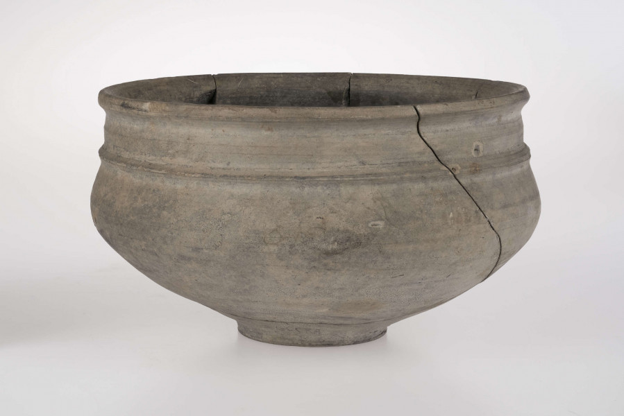 Naczynie o wklęsłym dnie, z dołkiem w centralnej części. Dno wyodrębnione niewysoką stopką. Brzusiec łagodnie profilowany. Szyjka podkreślona plstyczną listwą, w części środkowej nieco wypukła. Krawędź wylewu delikatnie wywinięta na zewnątrz. 