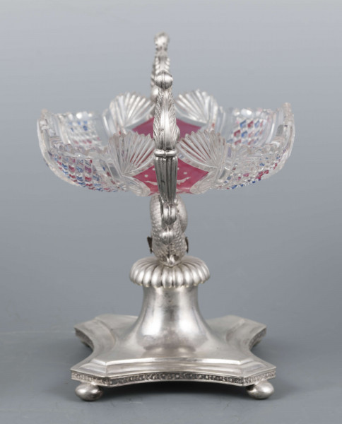 S/Mt/384/ML - Czara ze szkła bezbarwnego, miejscami barwionego powierzchniowo, płytka, owalna, profilowana, z dekoracją szlifowaną (wachlarzyki i szlif brylantowy) i trawioną (wzór kwiatowy) - utrzymana w stylu biedermeier. Umieszczona na figurce delfina z podstawą czworoboczną o wklęsłych bokach i ściętych narożach, z nóżkami w kształcie spłaszczonych kulek. Po bokach czary ucha w formie wolut z liśćmi akantu i motywem łabędzi. Brzeg podstawy obiega pas wici różanej.
Na brzegu podstawy sygnatura wklęsła kursywą: 
-  