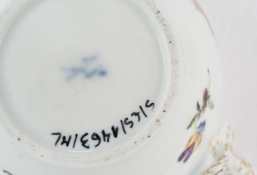 Imbryk kulisty lekko zwężony ku dołowi, wokół wylewu zdobiony plastyczną plecionka w typie Alt-Ozier. Dziobek rurkowy zakończony rozwartym smoczym pyskiem podkreślonym plastycznym liściem akantu. Ucho rokokowe w kształcie litery 