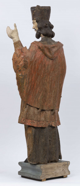 E/16816/ML - Rzeźba drewniana, pełna, polichromowana, przedstawiająca św. Jana Nepomucena. Kompozycja frontalna. Postać stojąca w kontrapoście – prawa noga zgięta i wysunięta do przodu. Sylwetka przechylona na prawo. Lewa ręka zgięta w łokciu i wysunięta do przodu. Prawa zgięta, uniesiona do góry. Brak atrybutów (krzyża i palmy) w dłoniach.
Postać ubrana w sutannę, komżę drapowaną w fałdy i zakończoną koronką, płaszcz z kapturem. Ślady złoceń na partii ubrania. Głowa skierowana na prawo. Twarz podłużna (kolor kremowy), usta proste, oczy z zaznaczonymi na ciemno tęczówkami, nos prosty, lekko zaznaczone kości policzkowe. Wolutowe pukle brody i włosów, symetryczne. Na głowie ciemnobrązowy biret. Stopy wystające spod sutanny.

Konserwacja: 2001 r.
